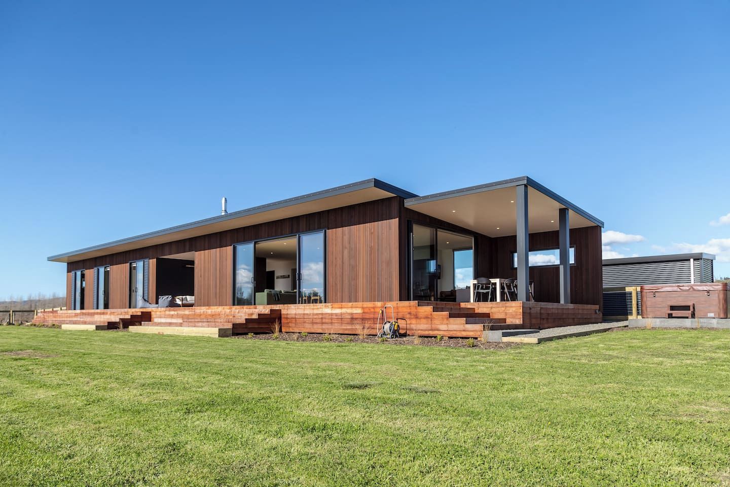 Una casa moderna de dos pisos con una amplia terraza, un espacio exterior cubierto y un interior espacioso con muebles a la vista.