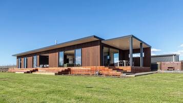 Una casa moderna de dos pisos con una amplia terraza, un espacio exterior cubierto y un interior espacioso con muebles a la vista.