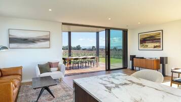 A modern living room with a marble coffee table, a sofa, and a dining area with a view of the outdoors.