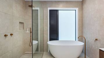 Un baño moderno con una bañera independiente, ducha con mampara de vidrio y un diseño minimalista.
