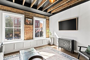 Een moderne woonkamer met grote ramen, een open haard en een flatscreen televisie.