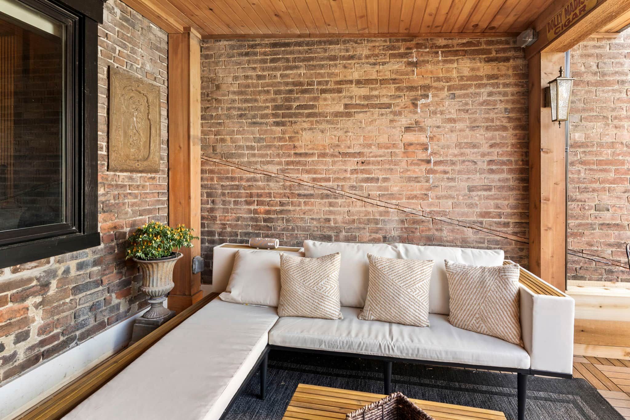 A cozy seating area with a sofa, cushions, a potted plant, and a wooden coffee table.