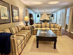 A living room with striped sofas, a coffee table, and framed pictures on the wall. - Lower Level Mountain Loft (Hot Springs)
