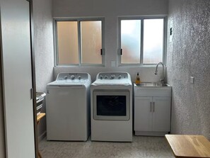 Uma lavanderia compacta com duas máquinas de lavar, uma secadora e uma pia.