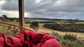 A room with a view of a landscape including a lake, trees, and hills.