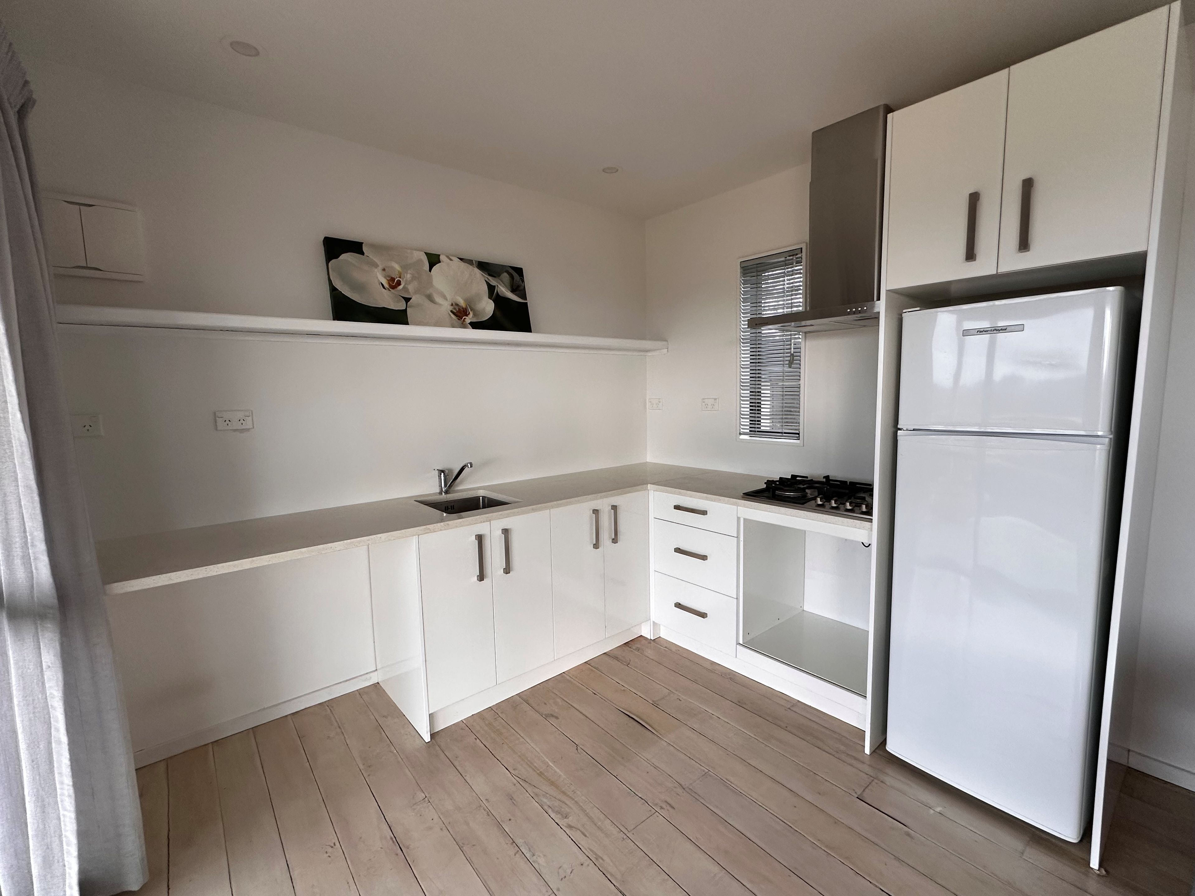 A modern kitchen with white cabinets, a stainless steel sink, and a built-in oven.