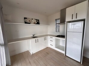 A modern kitchen with white cabinets, a stainless steel sink, and a built-in oven.