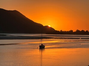 Ein Boot auf ruhigem Wasser bei Sonnenuntergang, im Hintergrund ein Berg.