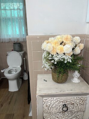 A bathroom with a toilet, a sink, and a decorative vase with flowers on a cabinet. - Spacious 4-bedroom house in quaint rural Barbourville surrounded by the mountain (Barbourville)