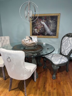 A dining area with a glass table surrounded by upholstered chairs, a decorative bowl, and a chandelier. - Spacious 4-bedroom house in quaint rural Barbourville surrounded by the mountain (Barbourville)