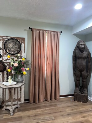 A room with a curtain, a clock, a statue, and a table with flowers. - Spacious 4-bedroom house in quaint rural Barbourville surrounded by the mountain (Barbourville)
