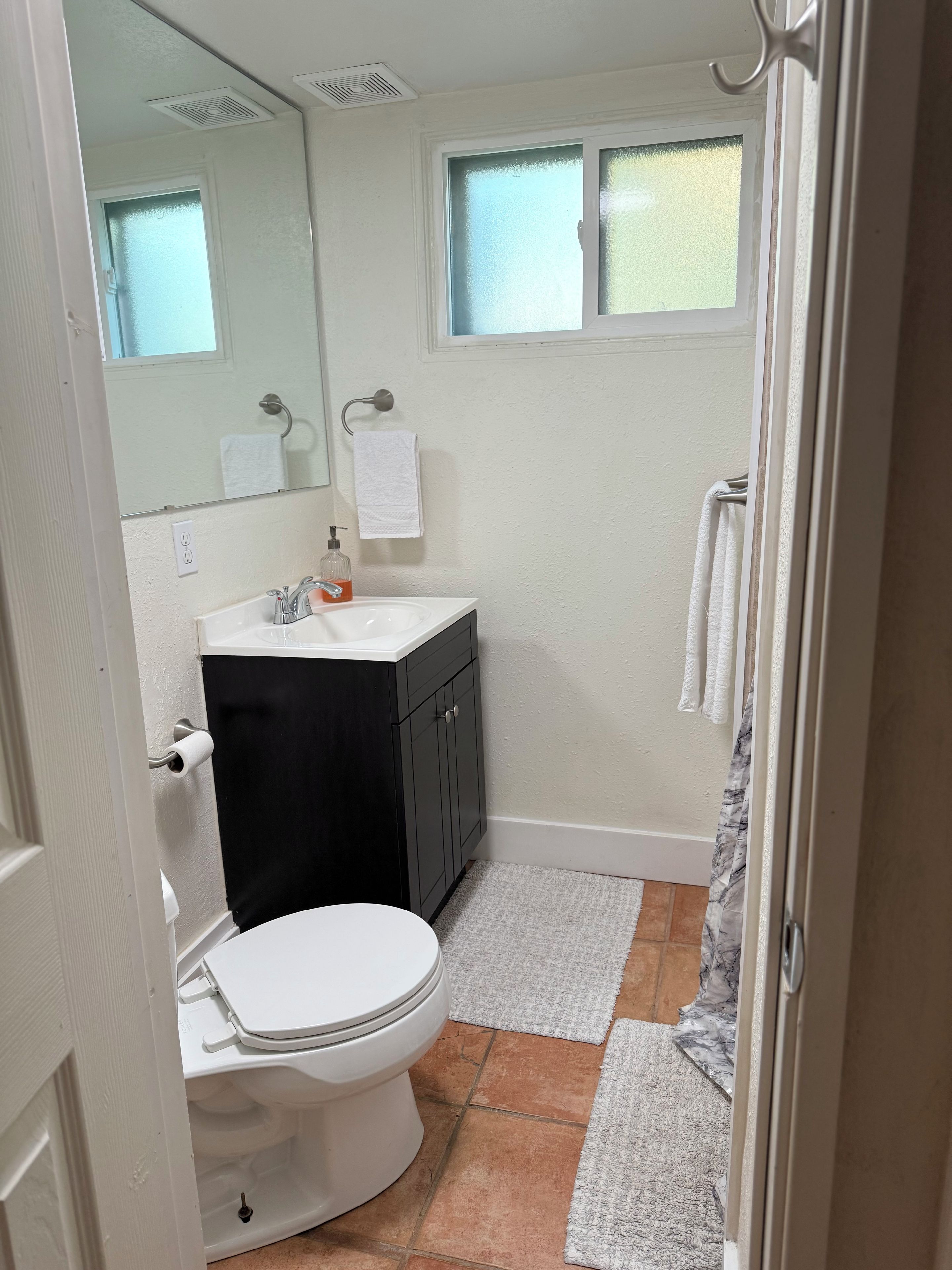 A bathroom with a toilet, sink, and mirror.