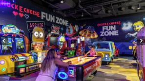 Eine Indoor-Spielhalle mit verschiedenen Spielautomaten und einer Minion-Maskottchen-Figur.