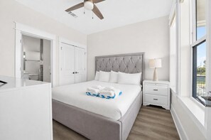 A hotel room with a bed, a nightstand, a lamp, a wardrobe, and a window. - One More Sunset, Across Street from Beach, Private Pool, Pet Friendly, Beach Gear Credit! (St. George Island)