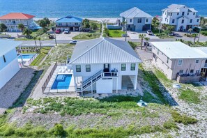 A coastal residential area with houses, a swimming pool, and a clear view of the ocean. - One More Sunset, Across Street from Beach, Private Pool, Pet Friendly, Beach Gear Credit! (St. George Island)