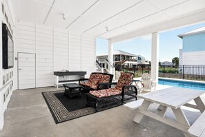 A covered outdoor area with a pool, two wicker chairs with floral cushions, a table, and a bench. - One More Sunset, Across Street from Beach, Private Pool, Pet Friendly, Beach Gear Credit! (St. George Island)