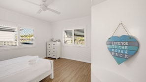 A bedroom with a bed, dresser, and two windows with blinds. - Rene's Cottage - a charming holiday rental nestled in the vibrant coastal town of Forster in NSW (Forster)
