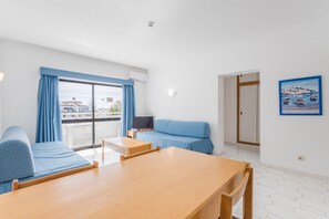 Ein modernes Hotelzimmer mit Balkon, einer Couch, einem Tisch und einem Fernseher.