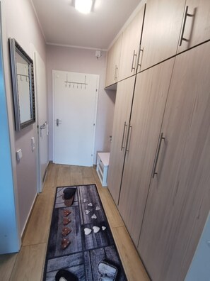 A narrow hallway with a wooden floor, a white door with a hanging coat rack, and a wardrobe with multiple doors. - Hanseat Vacation Rental, Apartment 174, with an ocean view and dog-friendly. (Grömitz)
