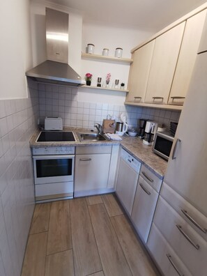 A compact kitchen with a stove, oven, sink, and dishwasher. - Hanseat Vacation Rental, Apartment 174, with an ocean view and dog-friendly. (Grömitz)