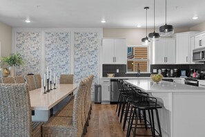 Una cuina moderna amb armaris blancs, una illa central i tamborets.