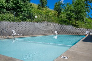 A swimming pool with clear water, surrounded by a stone wall and trees. - Magnolia Cottage-Walk In-Steps away from Pool-2 miles to Branson Strip (Branson)