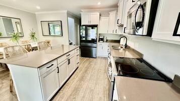 A modern kitchen with white cabinetry, a central island, and a black stovetop.