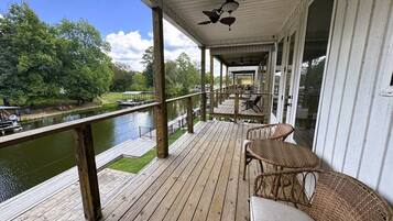 Een houten terras met rieten meubilair, uitkijkend op een wateroppervlak.
