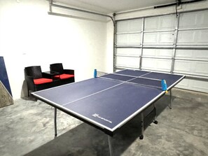 A ping pong table in a garage with a concrete floor and a garage door in the background.