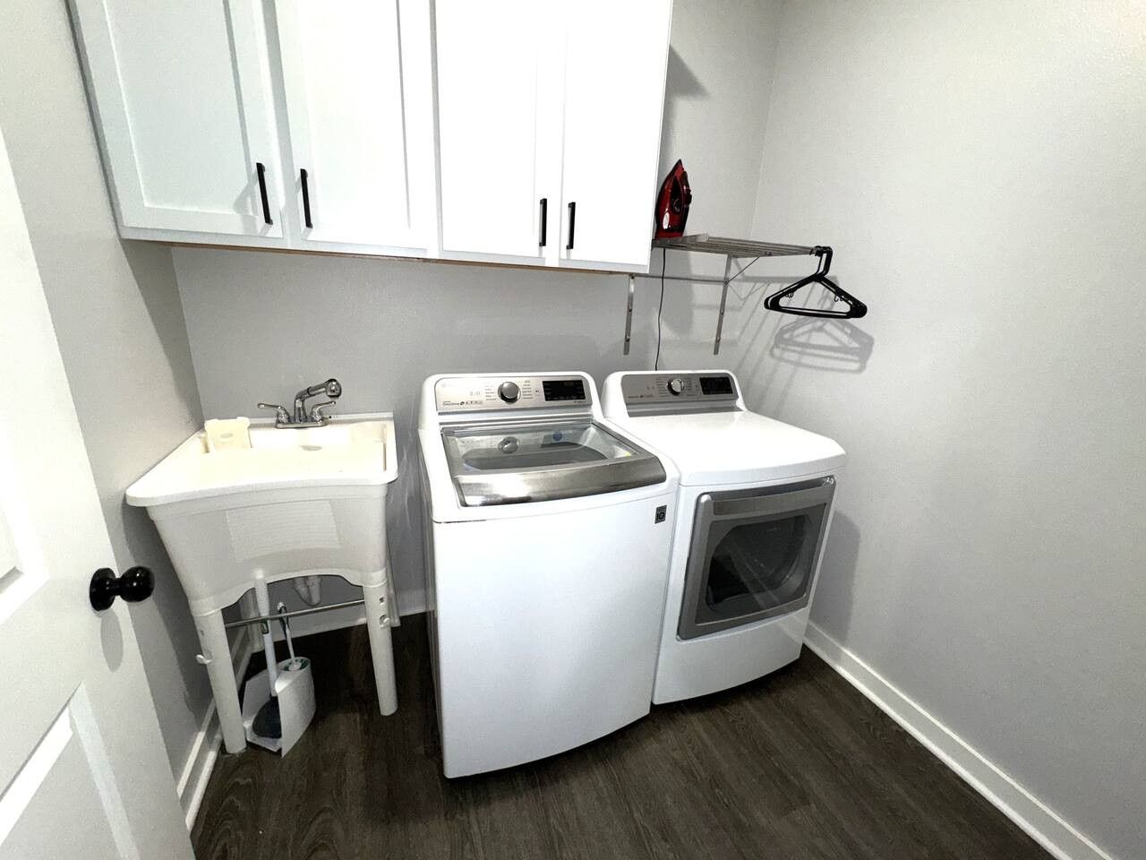 A compact laundry room with a sink, washing machine, and dryer.