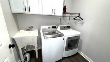A compact laundry room with a sink, washing machine, and dryer.
