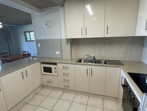 A kitchen with white cabinets, a microwave, a sink, and an oven. - 2 Bedroom Ocean-view Apartment (Gold Coast)