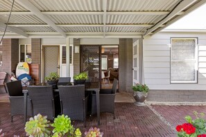 Une terrasse extérieure aménagée avec des meubles en osier et des plantes en pot.