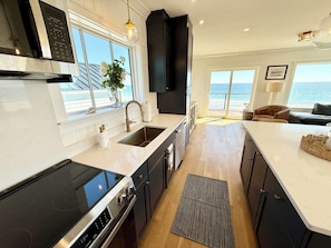 A modern kitchen with a large island, built-in appliances, and a view of the ocean.