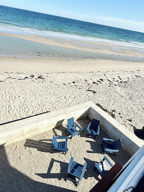 A beach with a concrete seating area and blue chairs.