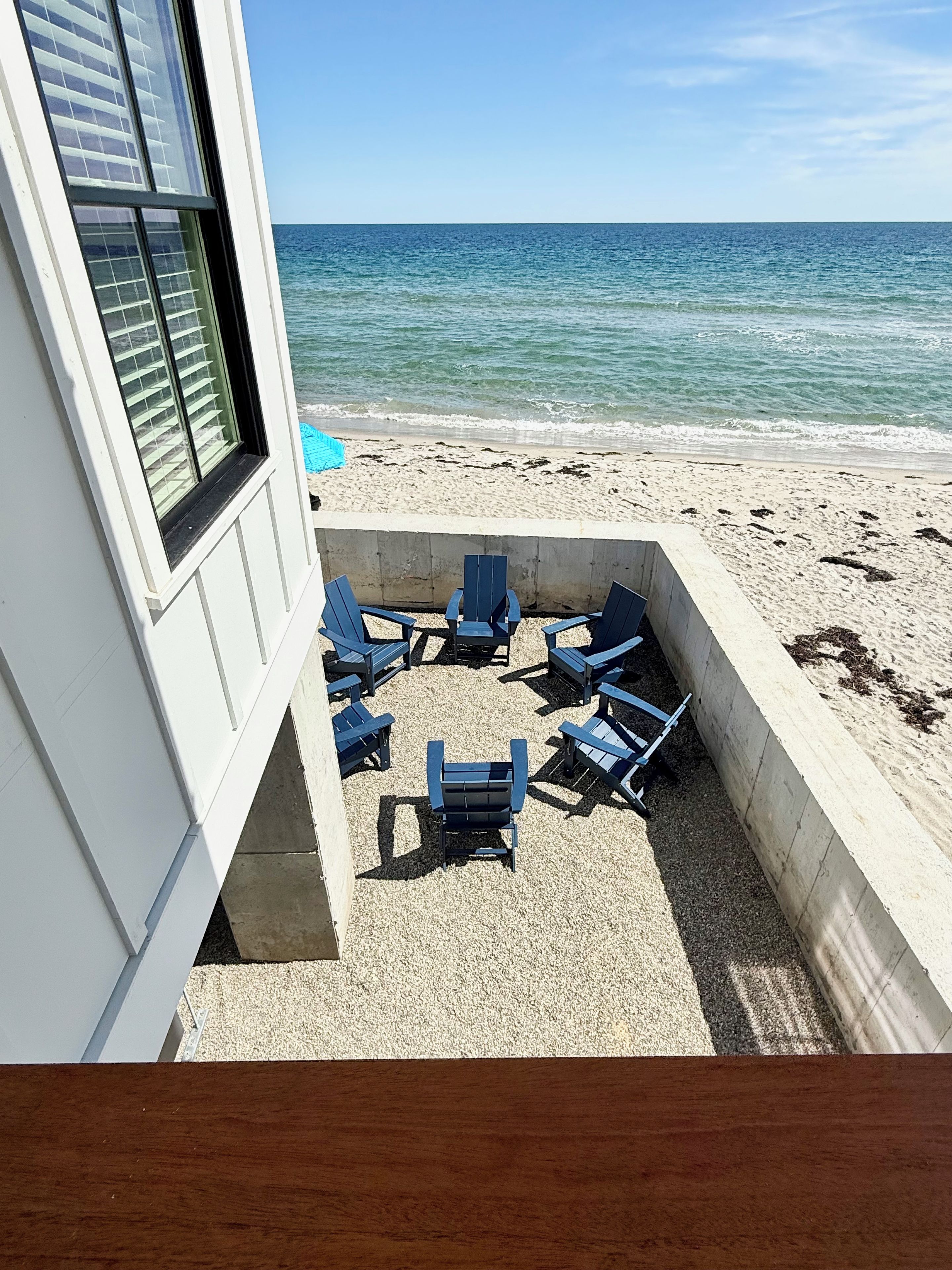 A beachside patio with outdoor seating and a view of the ocean.