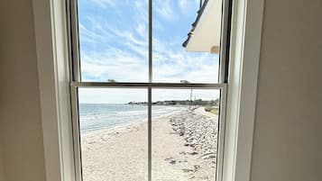 A room with a large window overlooking a beach.