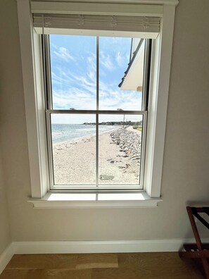 A room with a large window overlooking a beach.
