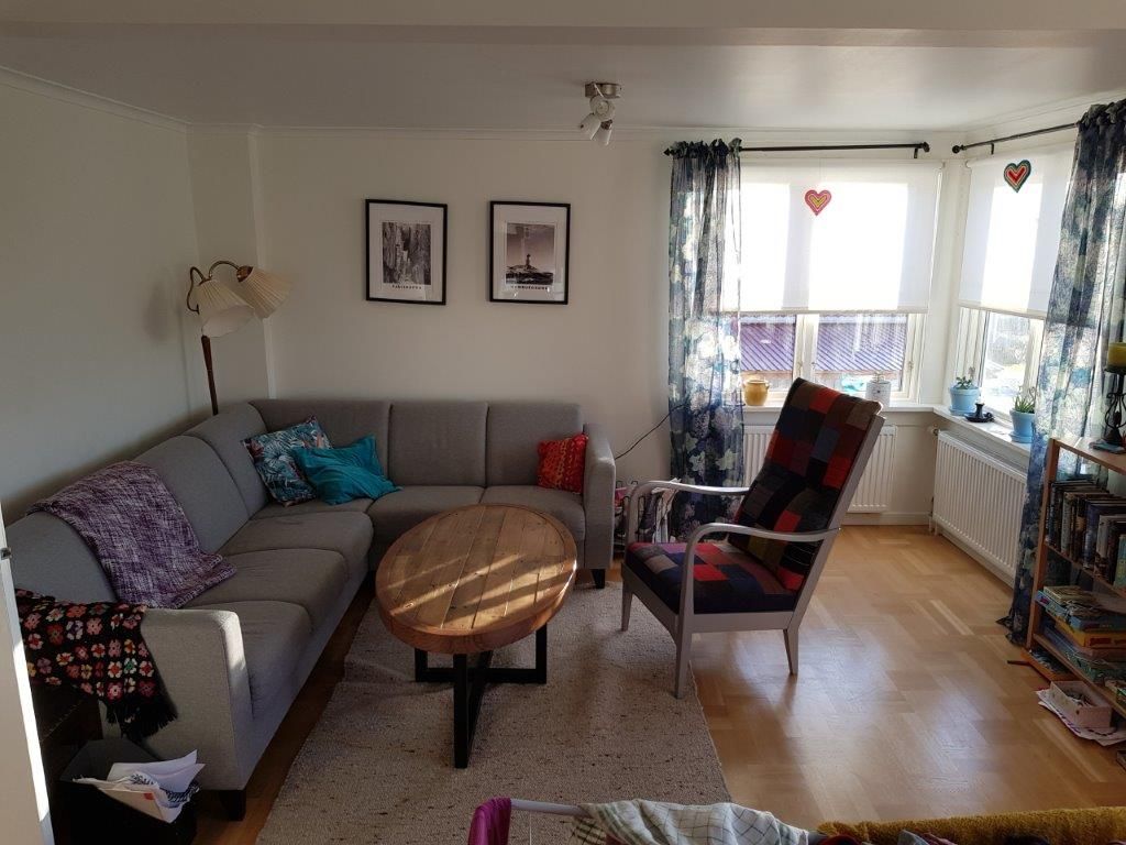 Ett vardagsrum med en soffa, en fåtölj, ett soffbord och en bokhylla.