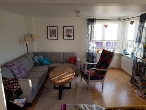 A living room with a sofa, armchair, coffee table, and a bookshelf.