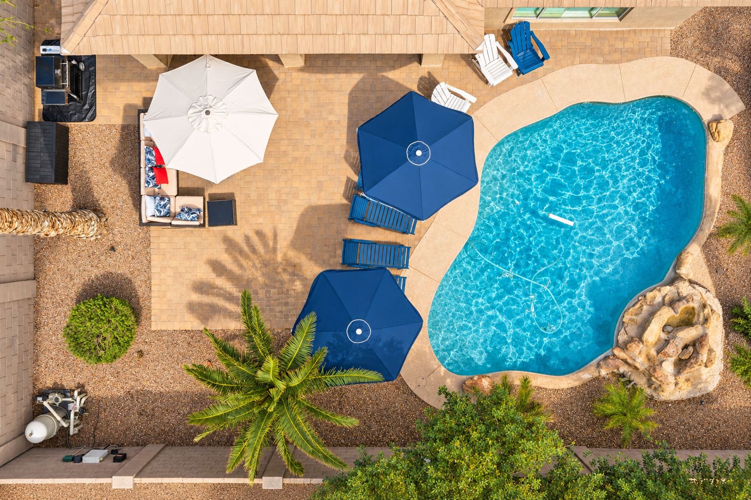 Area piscina sul tetto con poltronne, ombrelloni e un piccolo giardino.