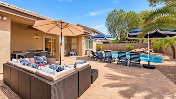 Eine Terrassenanlage mit Pool, Liegestühlen und einer überdachten Sitzgelegenheit.