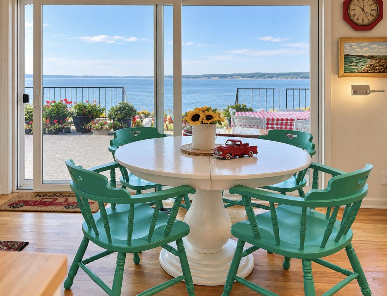 A round table with six chairs, a vase with sunflowers, and a toy truck on the table.