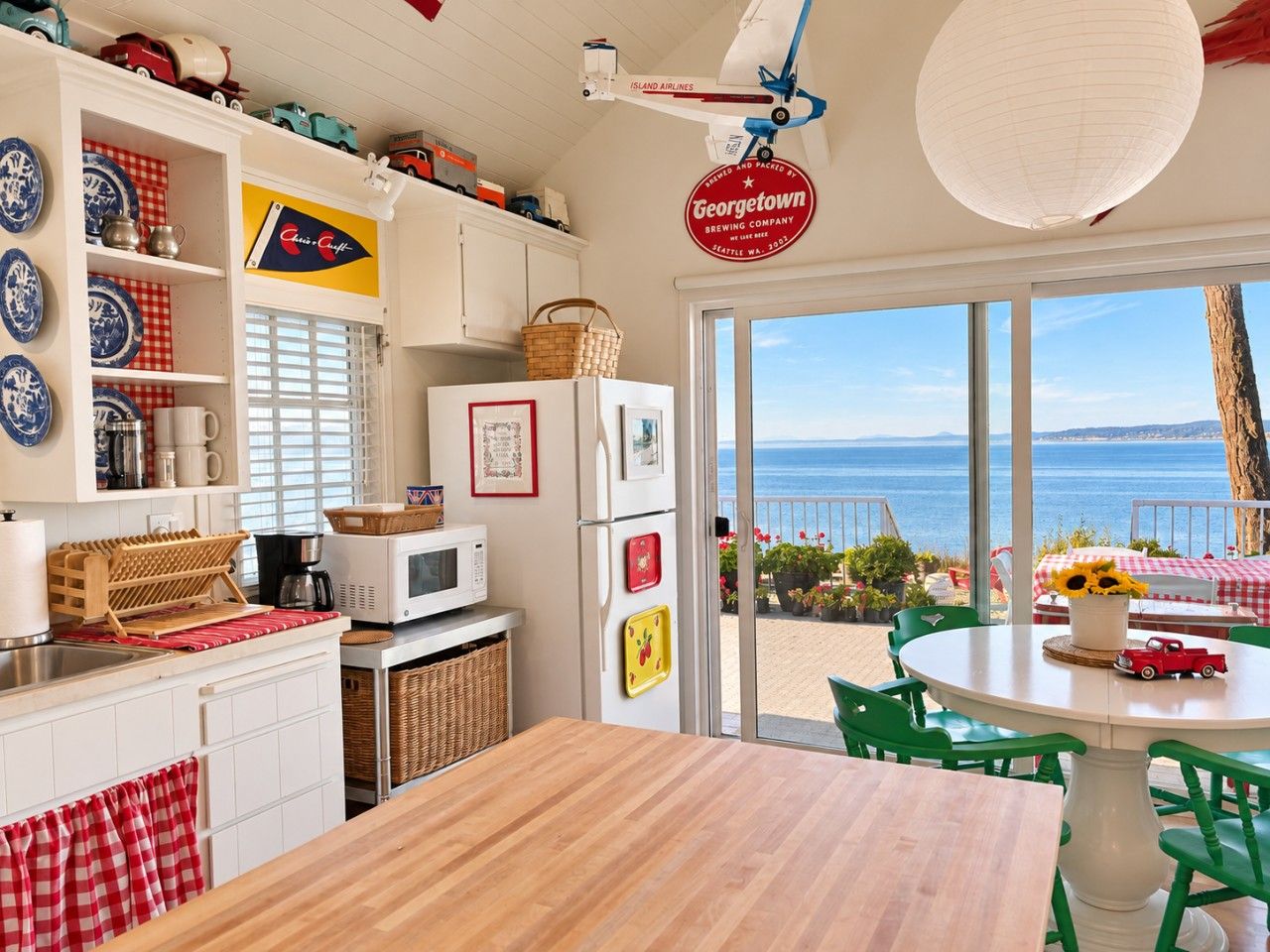 A kitchen with a view of the sea, a dining area with a table and chairs, and a hanging sign.