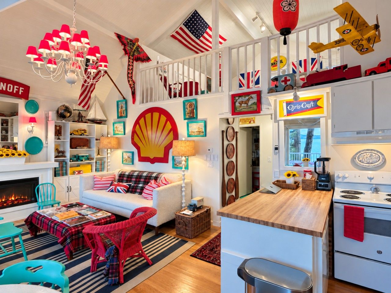 A living room with a fireplace, a sofa with a red and white checkered blanket, and a kitchen area with a stove and a sign that reads 'Chris-Craft.'
