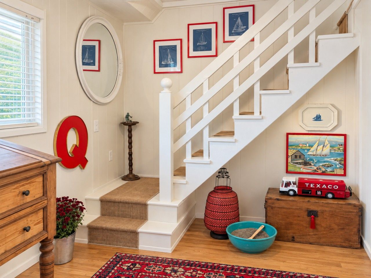 A staircase with white railings, a red letter 'Q' decoration, and nautical-themed wall art.