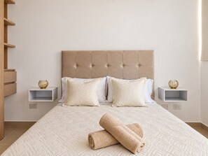 A hotel room with a large bed, two bedside tables, and a headboard. - Moesko Apartment (Gaira)