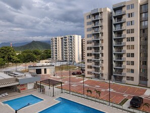 A residential building with multiple floors, balconies, and a parking area with a swimming pool. - Moesko Apartment (Gaira)