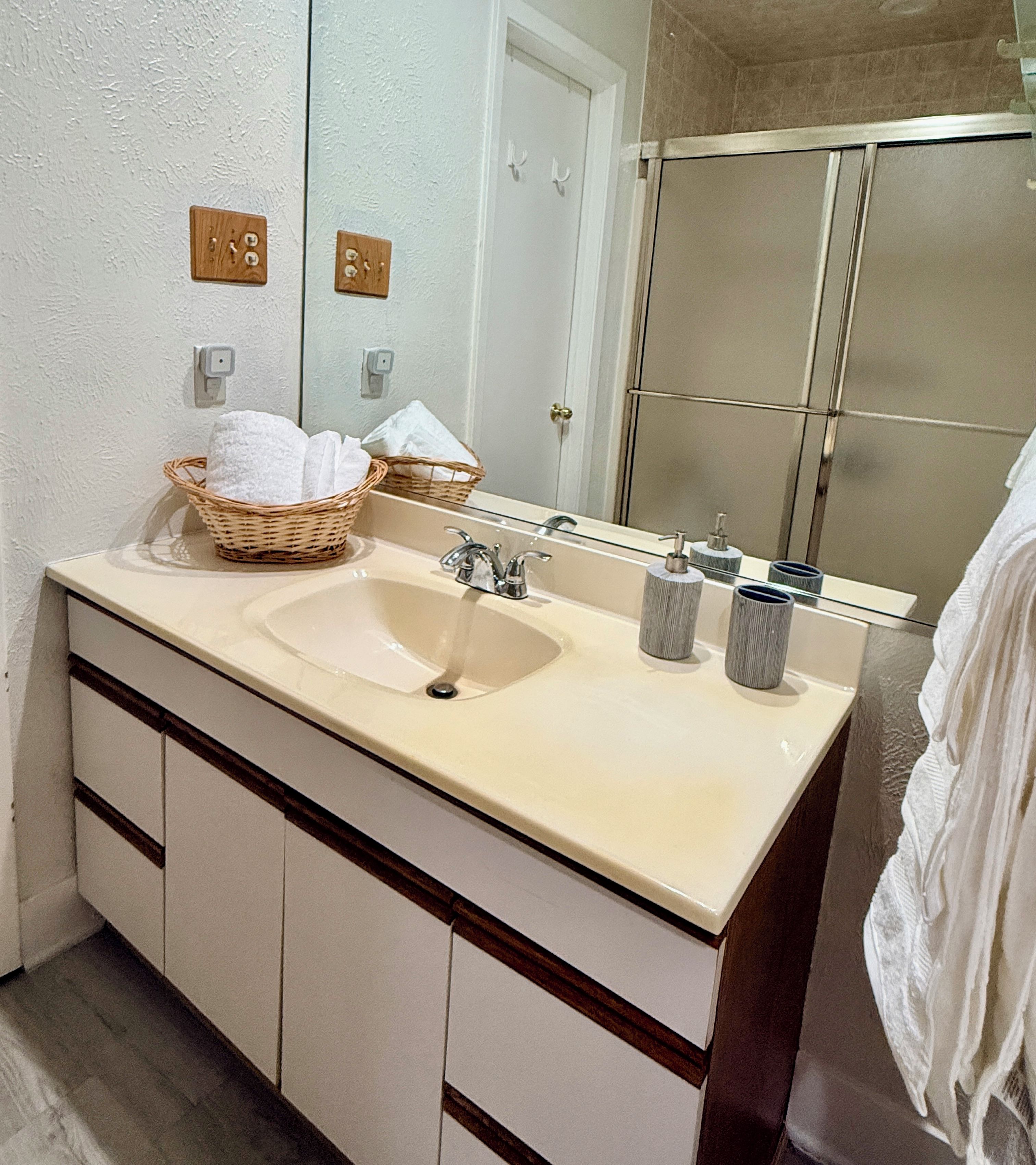 Un bagno con lavandino, specchio e portasciugamani.