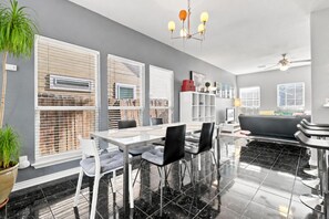A modern kitchen with a dining area, large windows, and a ceiling fan. - Alamodome~Backyard Games~Grill~Near Downtown (San Antonio)